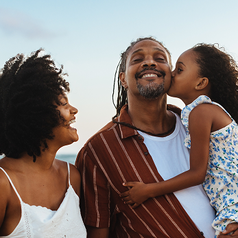Actor portrayal of parents with their child on the beach.